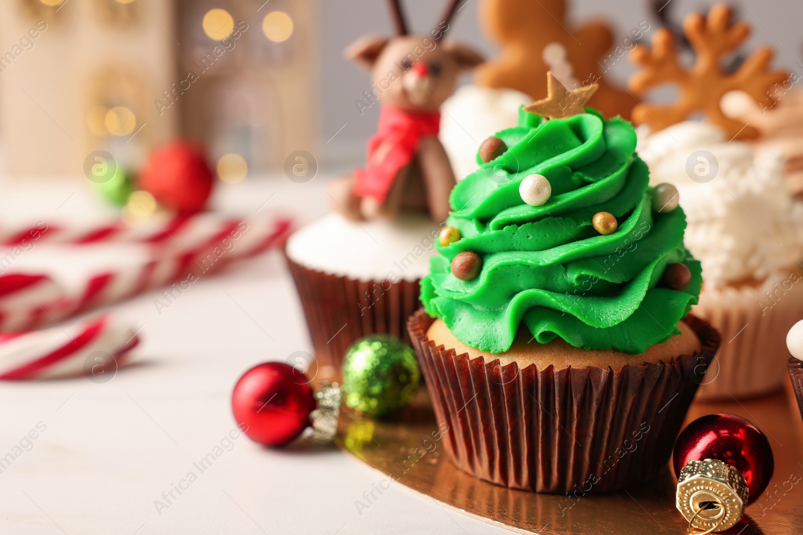 Photo of Tasty Christmas tree cupcake and baubles on white table. Space for text
