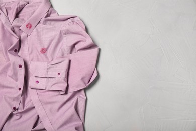 Photo of Men's shirt with lipstick kiss marks on light background, top view. Space for text