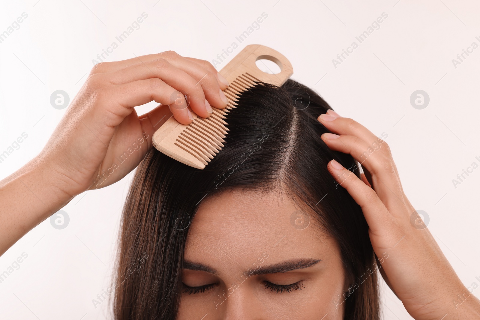 Photo of Woman with comb examining her hair and scalp on white background, closeup