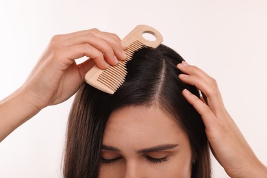 Photo of Woman with comb examining her hair and scalp on white background, closeup