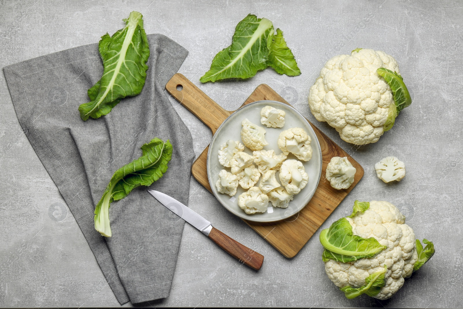 Photo of Cut and whole cauliflowers on grey table, flat lay