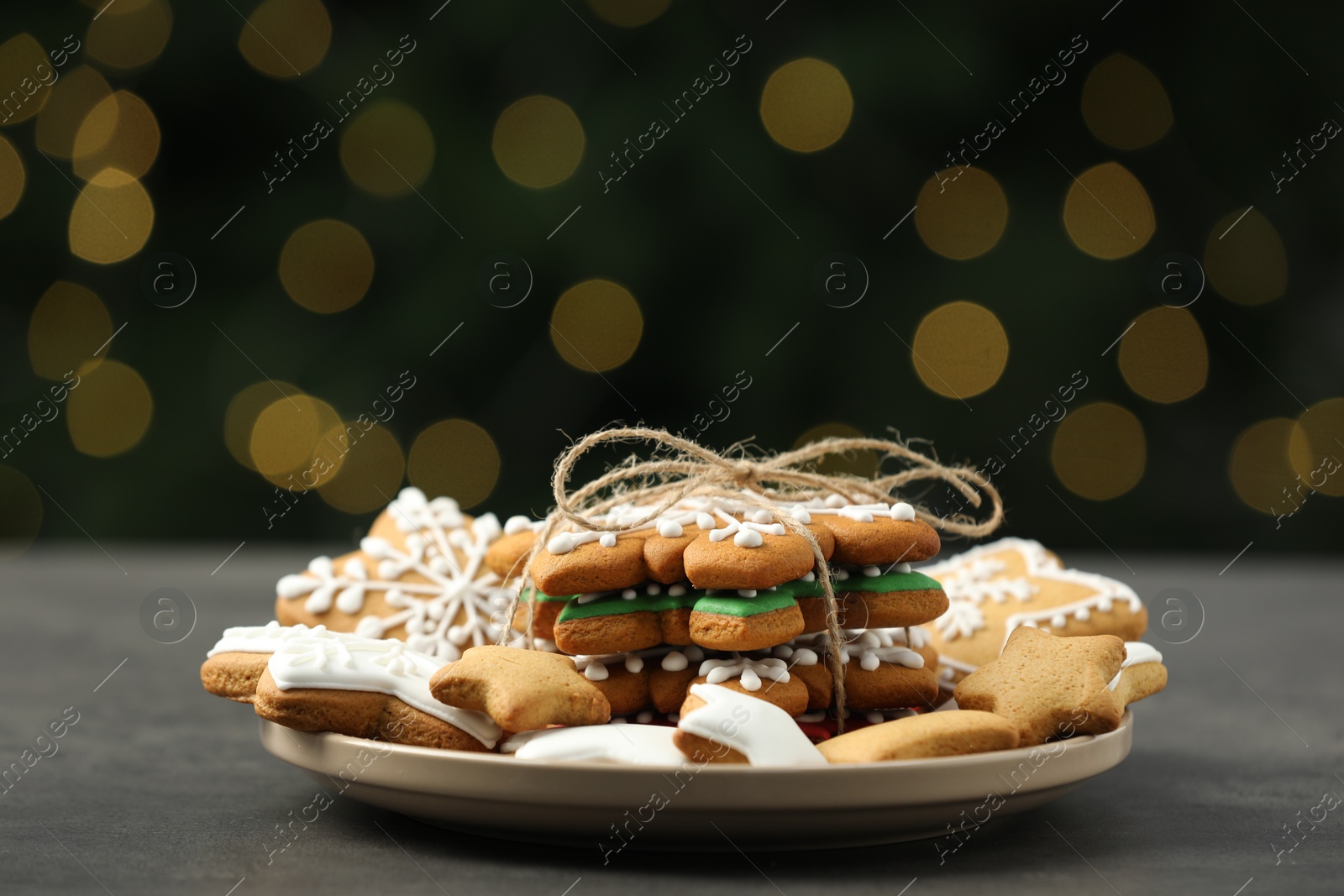 Photo of Decorated cookies on grey table against blurred Christmas lights