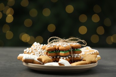 Decorated cookies on grey table against blurred Christmas lights