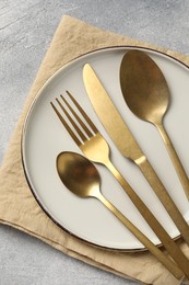 Photo of Stylish cutlery, plate and napkin on light grey table, top view