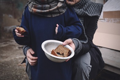 Image of Poor father and child with bread at dump, closeup