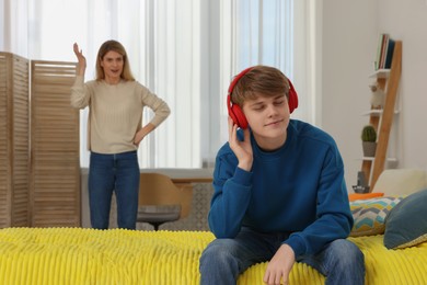 Teenage son in headphones ignoring his mother at home