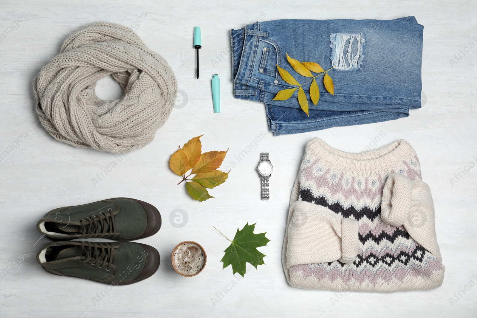 Photo of Stylish outfit and autumn leaves on white wooden background, flat lay. Trendy warm clothes