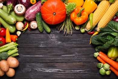 Different fresh vegetables on black wooden table, flat lay. Space for text