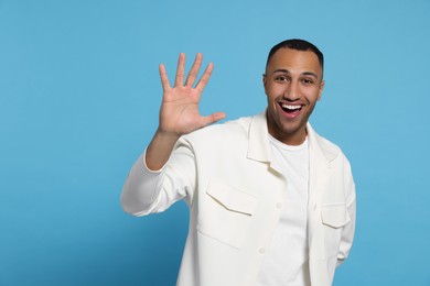Man giving high five on light blue background. Space for text