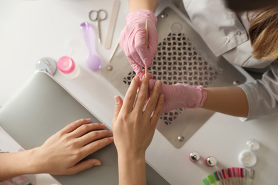 Photo of Professional manicurist working with client in beauty salon, top view