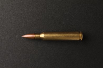 Photo of One bullet on black background, top view