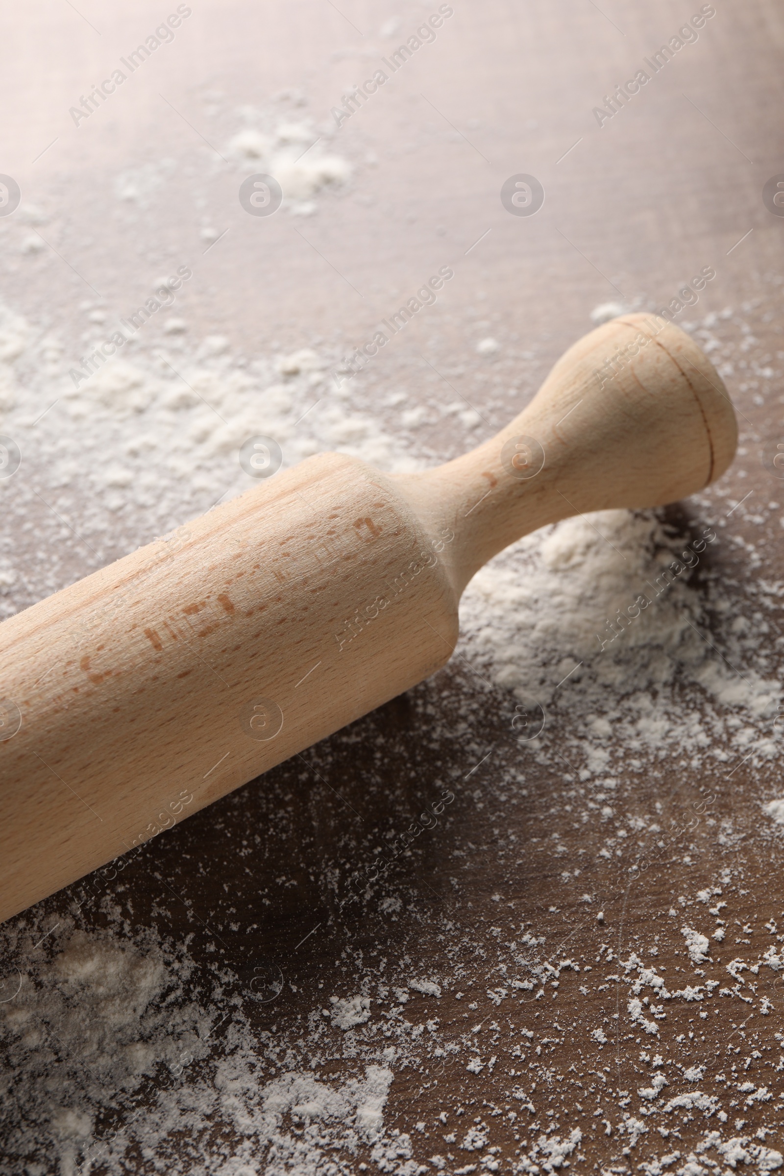 Photo of Rolling pin and scattered flour on wooden table, closeup