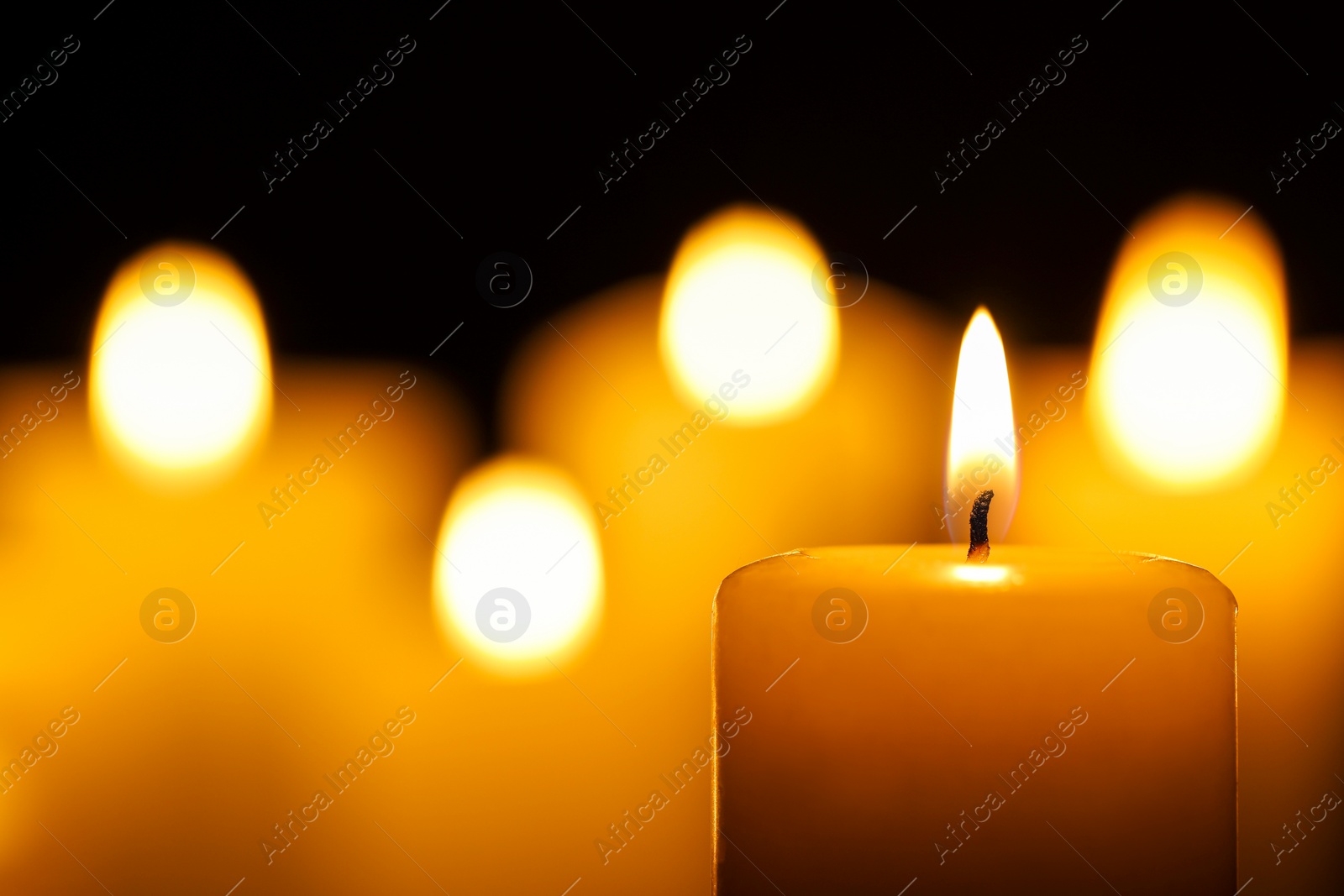 Photo of Burning candle on black background, closeup. Space for text