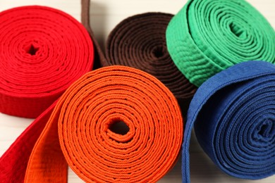 Photo of Colorful karate belts, closeup. Martial arts uniform