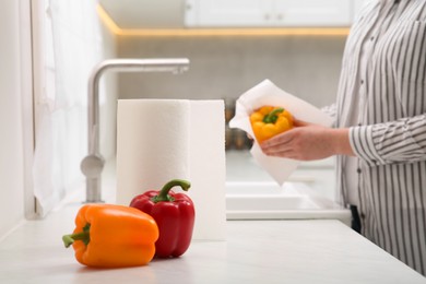 Photo of Woman wiping bell pepper with paper towel in kitchen, closeup. Space for text