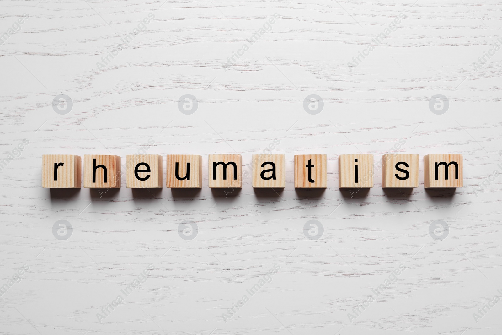 Photo of Word Rheumatism made of cubes on white wooden table, top view