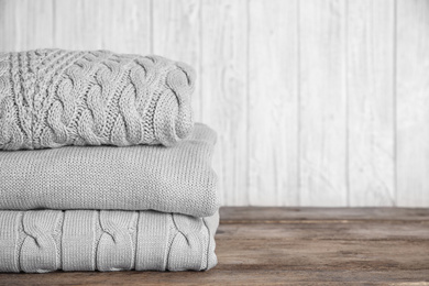 Image of Stack of folded warm sweaters on wooden table. Space for text