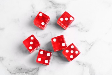 Many red game dices on white marble table, flat lay