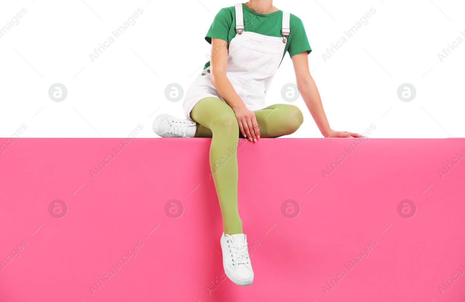 Photo of Woman wearing green tights and stylish shoes sitting on color background, closeup