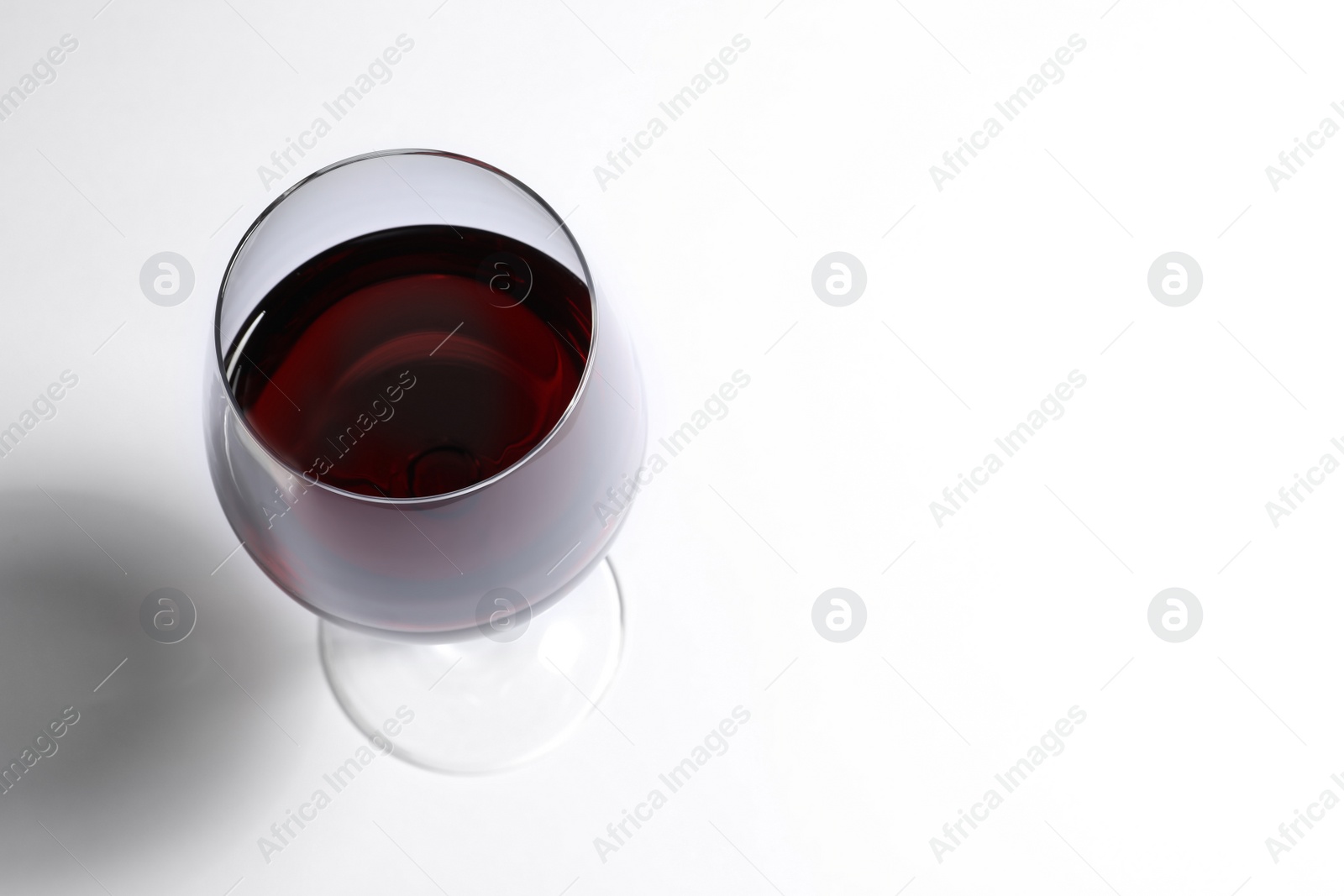 Photo of Glass of red wine on white background, above view. Space for text