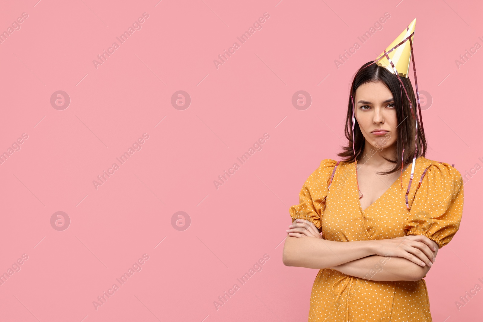 Photo of Sad young woman in party hat on pink background