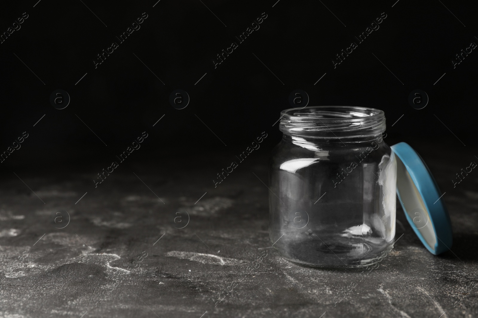 Photo of Empty glass jar on grey stone table, space for text