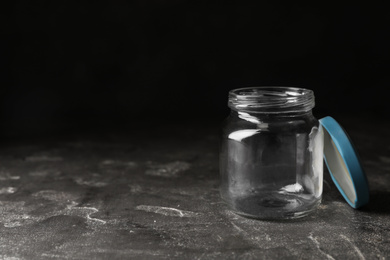 Empty glass jar on grey stone table, space for text