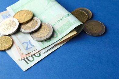 Photo of Euro banknotes and coins on blue background, closeup