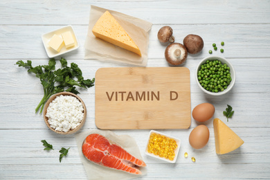 Photo of Flat lay composition with products rich in vitamin D on white wooden table. Space for text