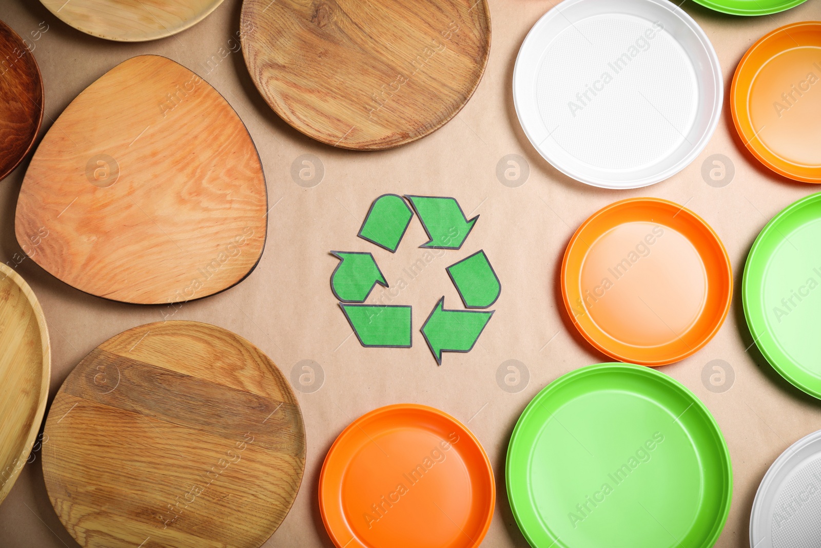 Photo of Recycling symbol, plastic and wooden plates on beige background, flat lay