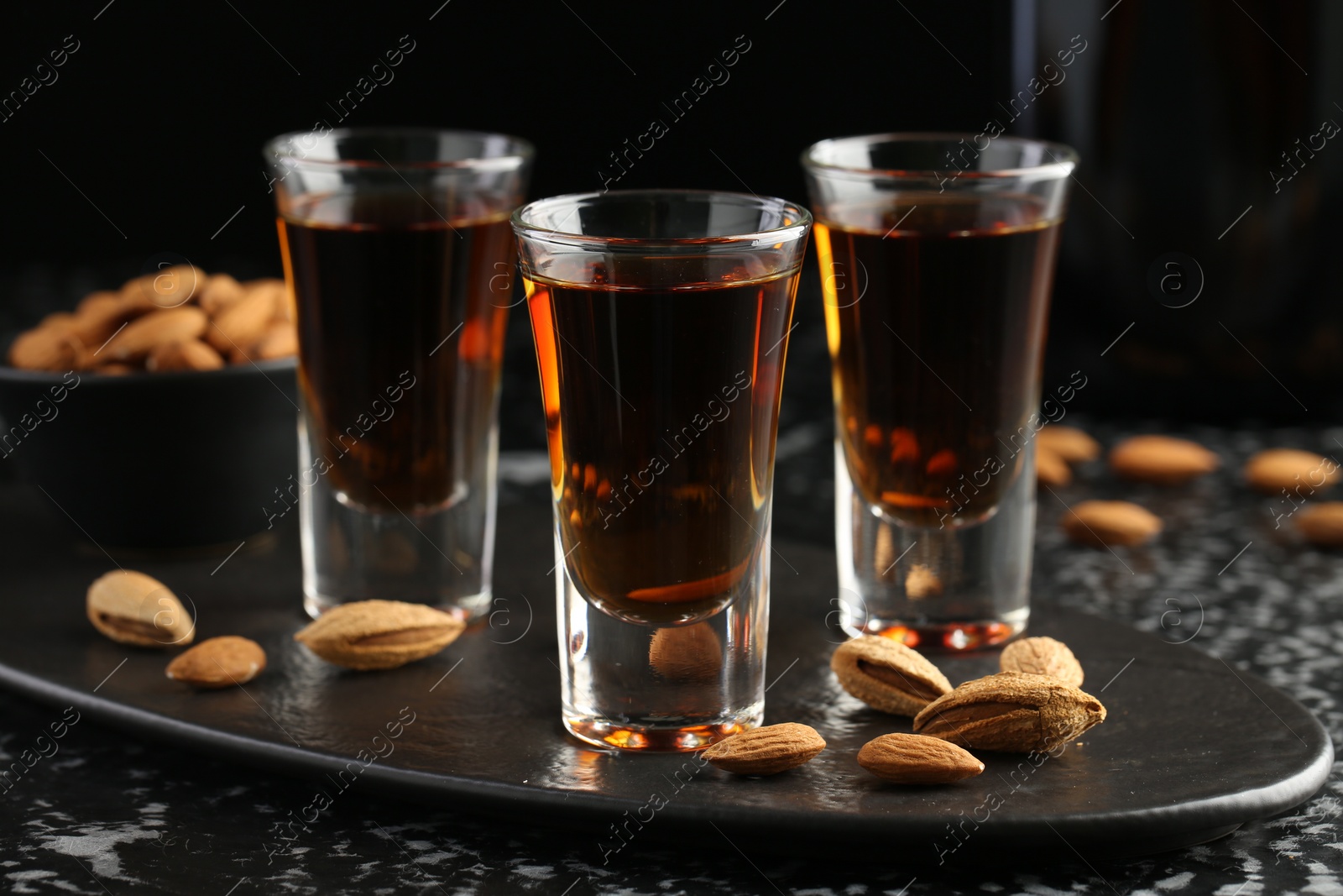 Photo of Glasses with tasty amaretto liqueur and almonds served on table, closeup