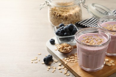 Photo of Glasses of tasty blueberry smoothie with oatmeal on wooden table. Space for text