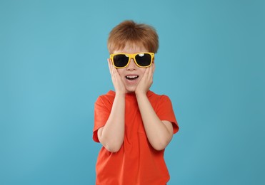 Cute little boy with sunglasses on light blue background