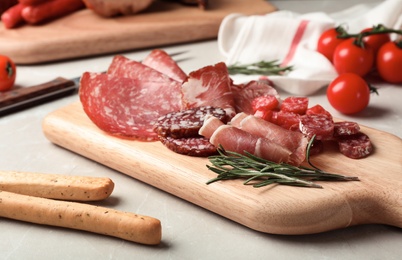 Photo of Cutting board with different meat delicacies on gray table