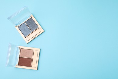 Beautiful eye shadow palettes on light blue background, flat lay. Space for text