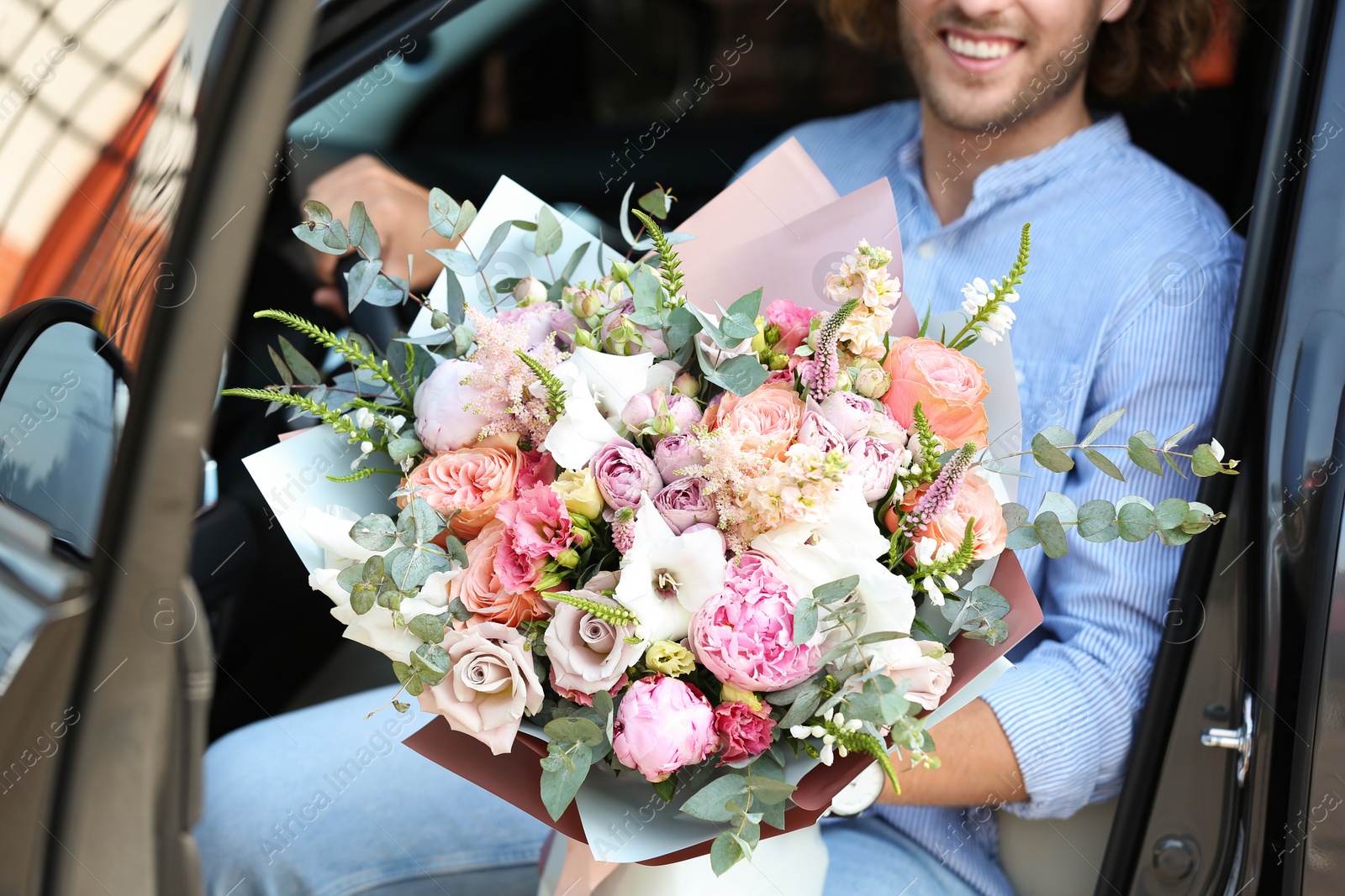 Photo of Man with beautiful flower bouquet in car, closeup