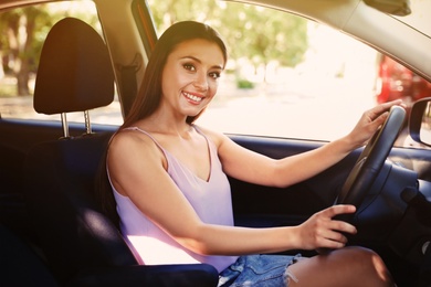 Happy young beautiful woman driving modern car