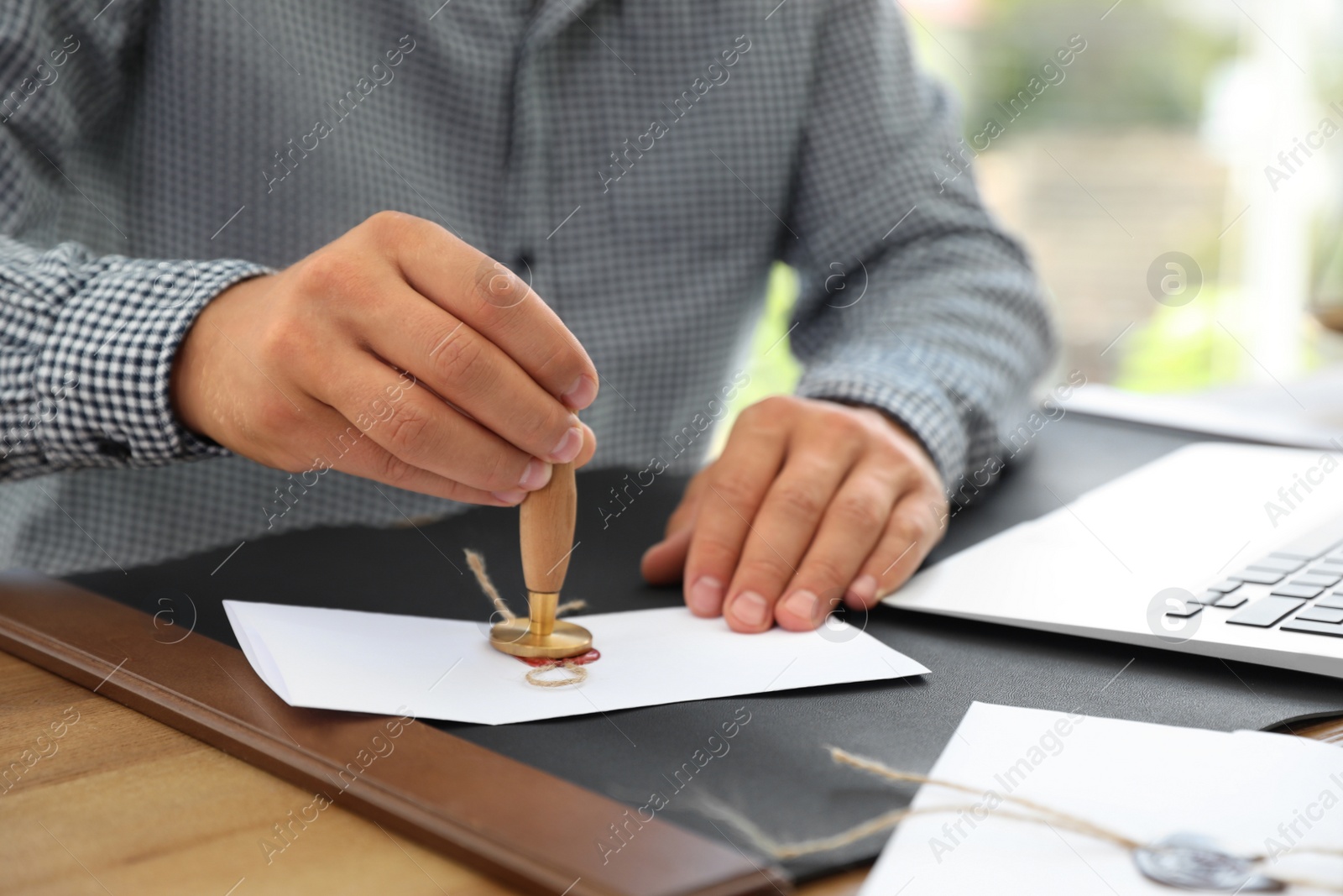 Photo of Male notary stamping document at table in office, closeup