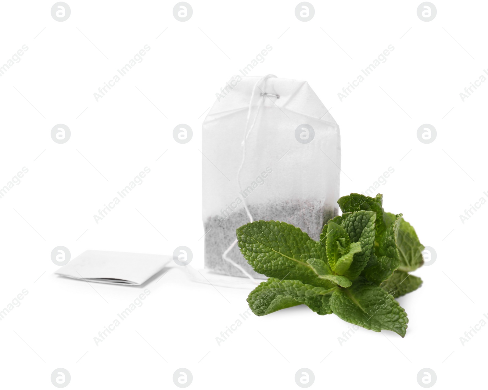 Photo of New tea bag with label and mint on white background