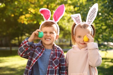 Photo of Cute little children with bunny ears holding Easter eggs in park