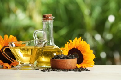 Sunflower cooking oil, seeds and yellow flowers on white wooden table outdoors, space for text