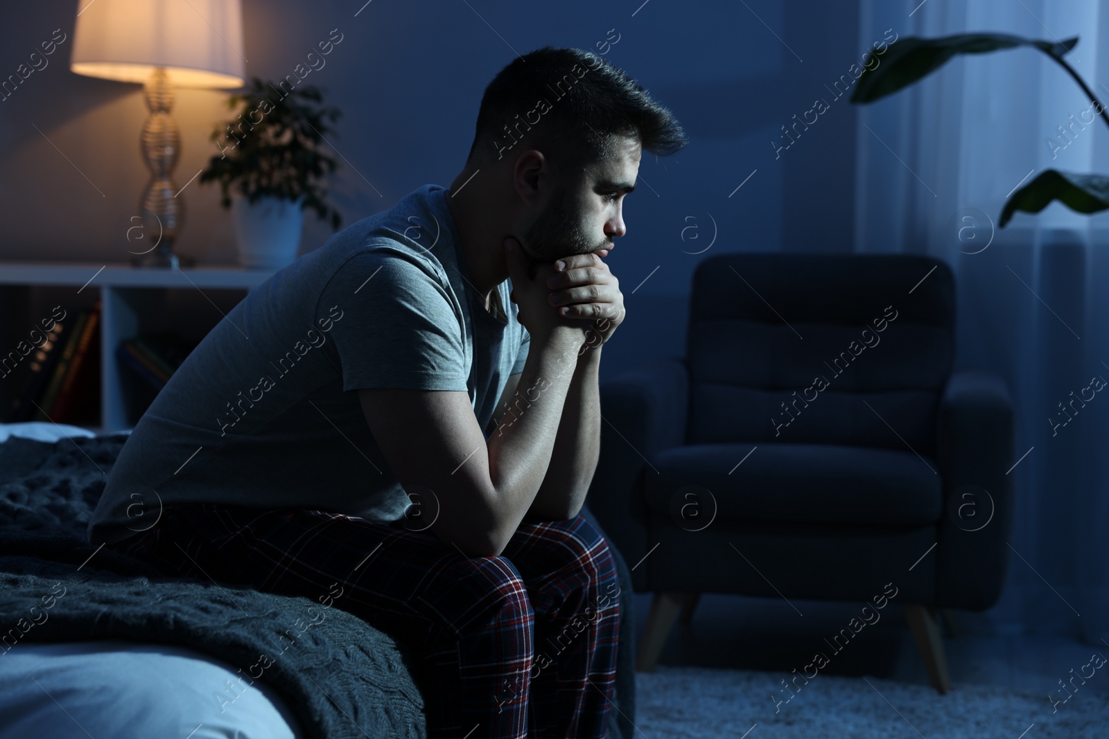 Photo of Frustrated man sitting on bed at night