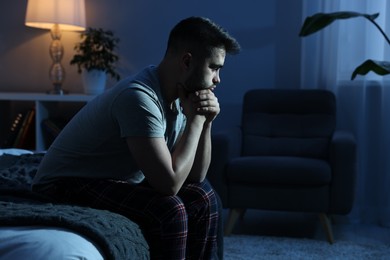 Photo of Frustrated man sitting on bed at night