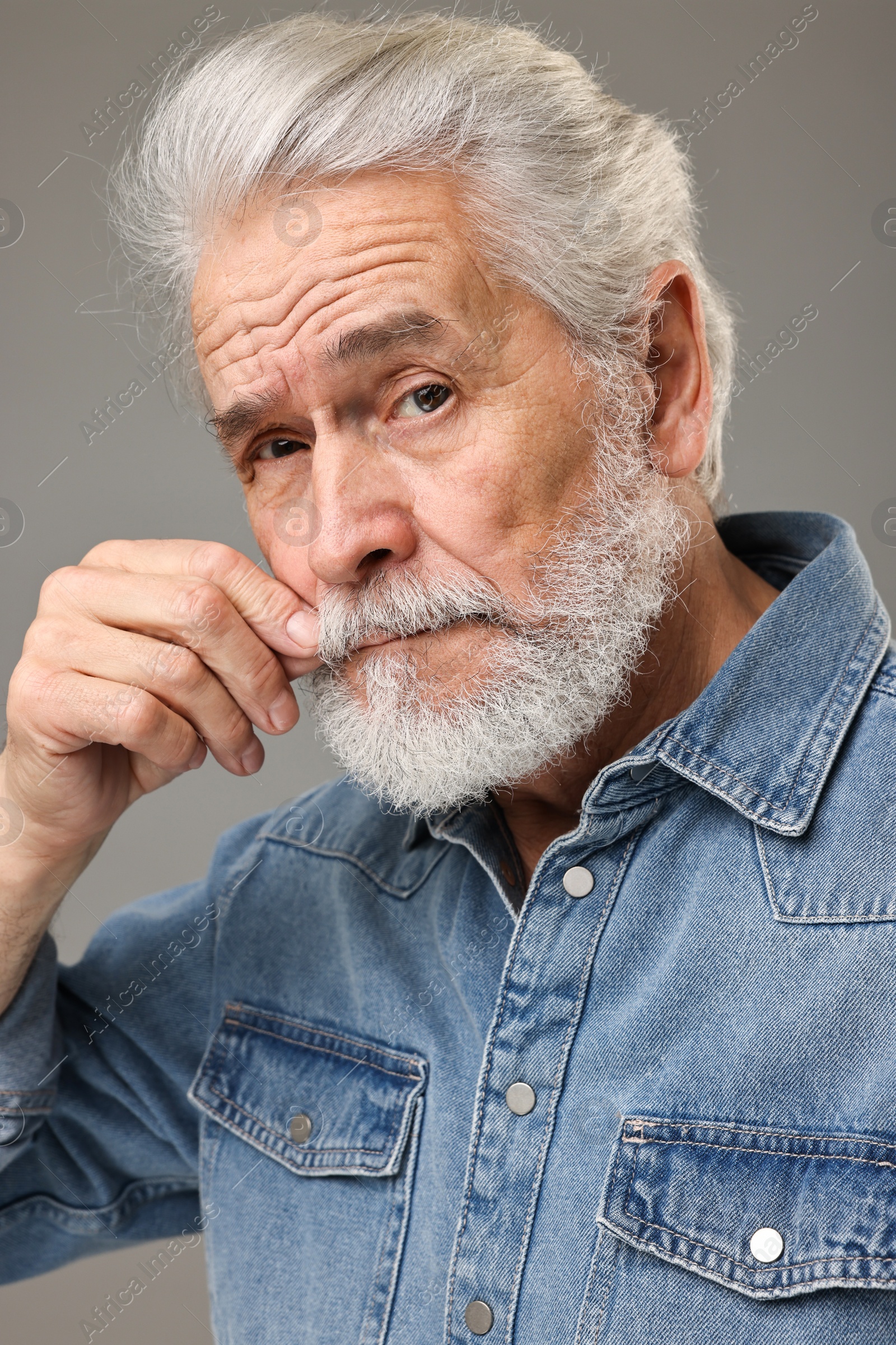 Photo of Senior man touching mustache on grey background