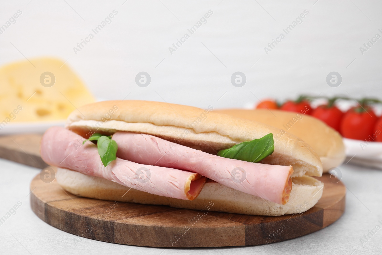 Photo of Delicious sandwich with ham and basil on white table, closeup