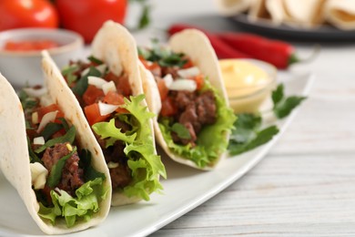 Photo of Delicious tacos with meat and vegetables on wooden table, closeup