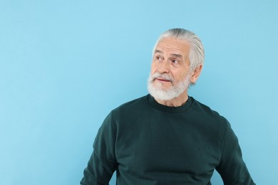 Portrait of handsome senior man on light blue background. Space for text