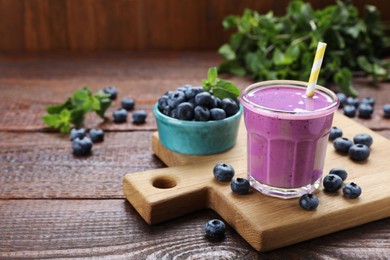 Glass of blueberry smoothie with mint and fresh berries on wooden table. Space for text