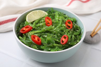 Tasty seaweed salad in bowl served on white table, closeup