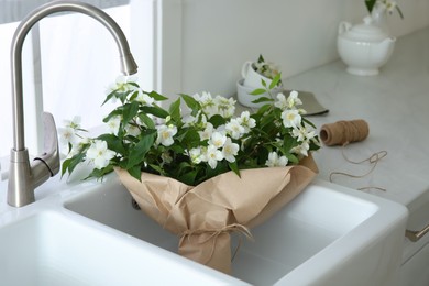 Photo of Bouquet with beautiful jasmine flowers in kitchen sink